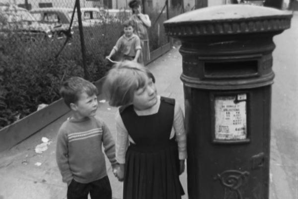 Still image from [Midlands News: 09.07.1963: Boy locked in pillarbox at Hockley]: a boy and a girl look up at a post box.